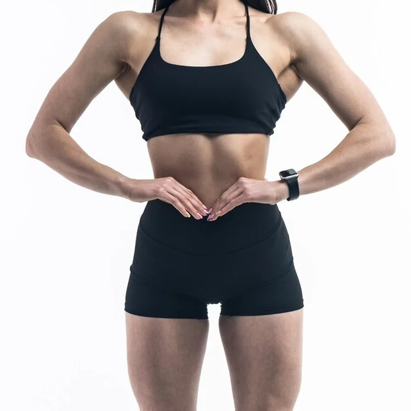 Kobieta w czarnym stroju sportowym pokazująca brzuch i mięśnie