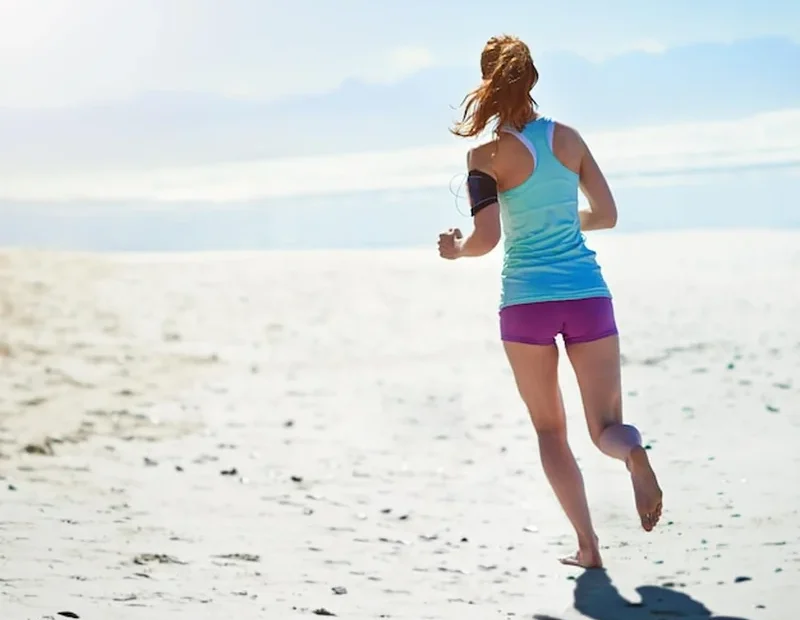 Kobieta biegnąca po piaszczystej plaży w treningu cardio