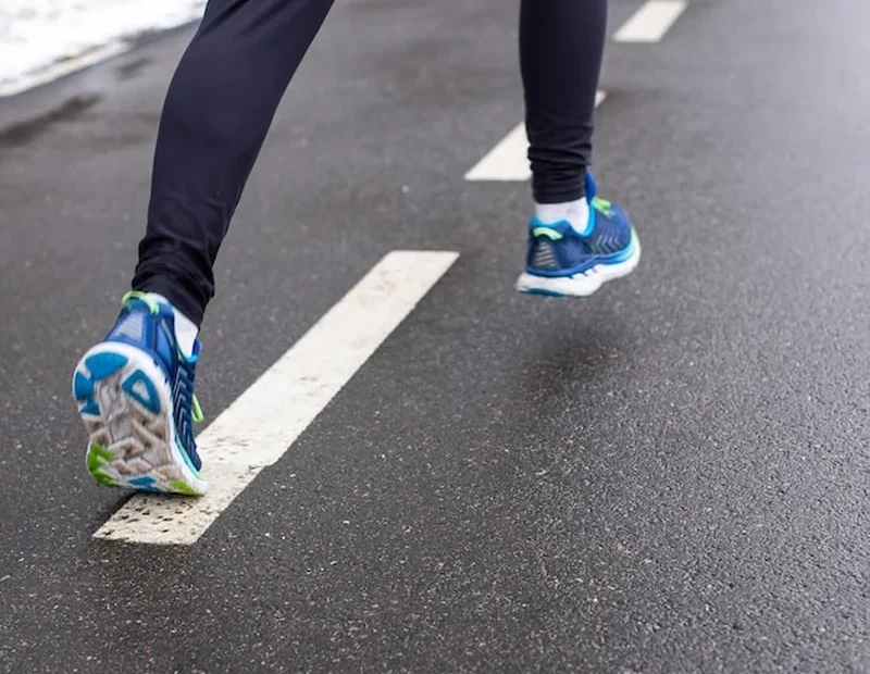 Biegacz w sportowych butach na torze drogowym