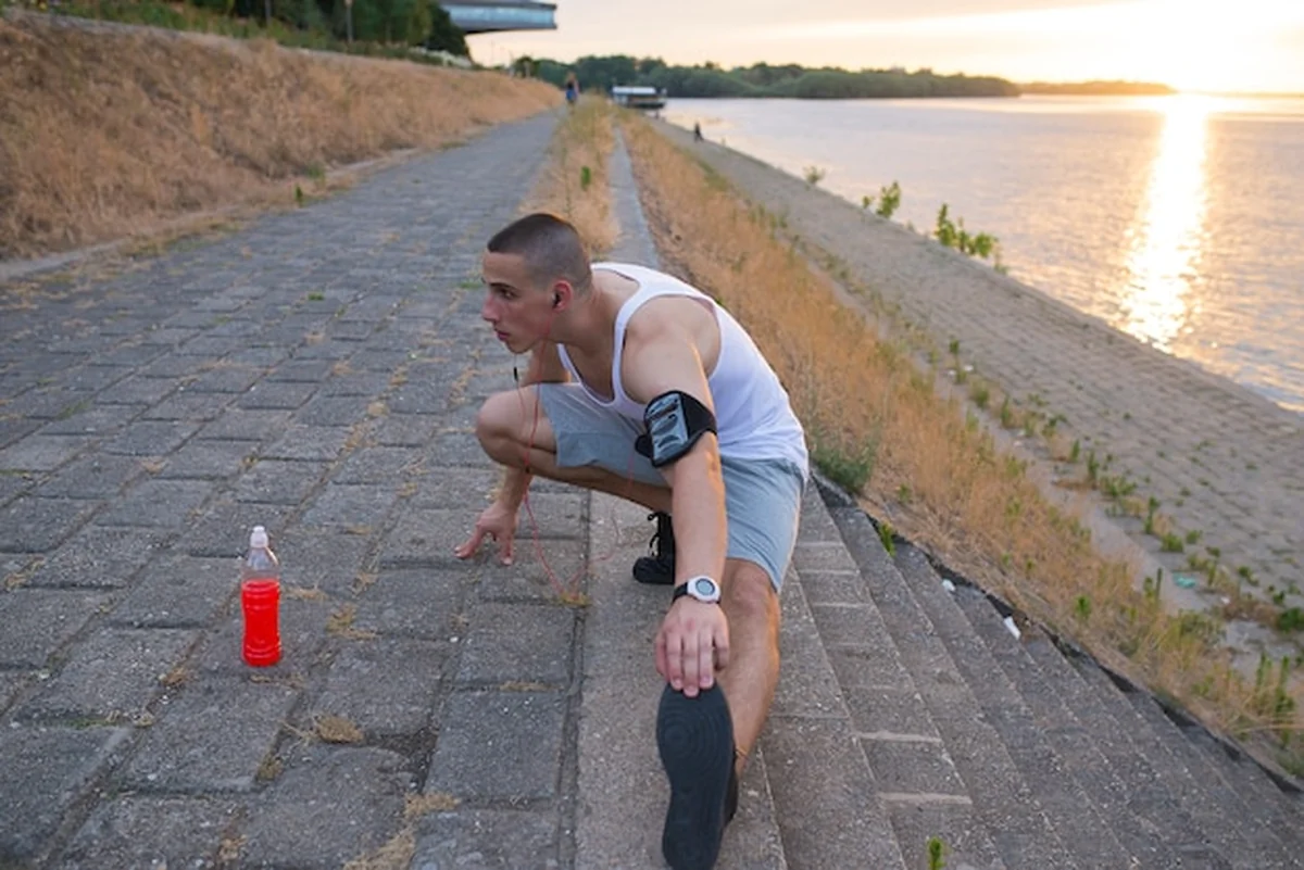 Młody fitness lekkoatleta rozciąga nogi przed treningiem