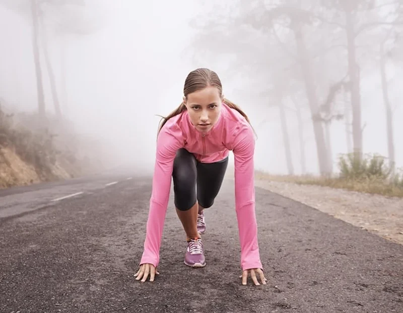 Młoda biegaczka w mglisty poranek gotowa do treningu biegowego